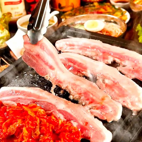 Pork belly and kimchi cooking on a grill in Churugida's restaurant photograph